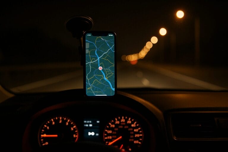 Dashboard view of smartphone mounted in car displaying live GPS map during nighttime driving